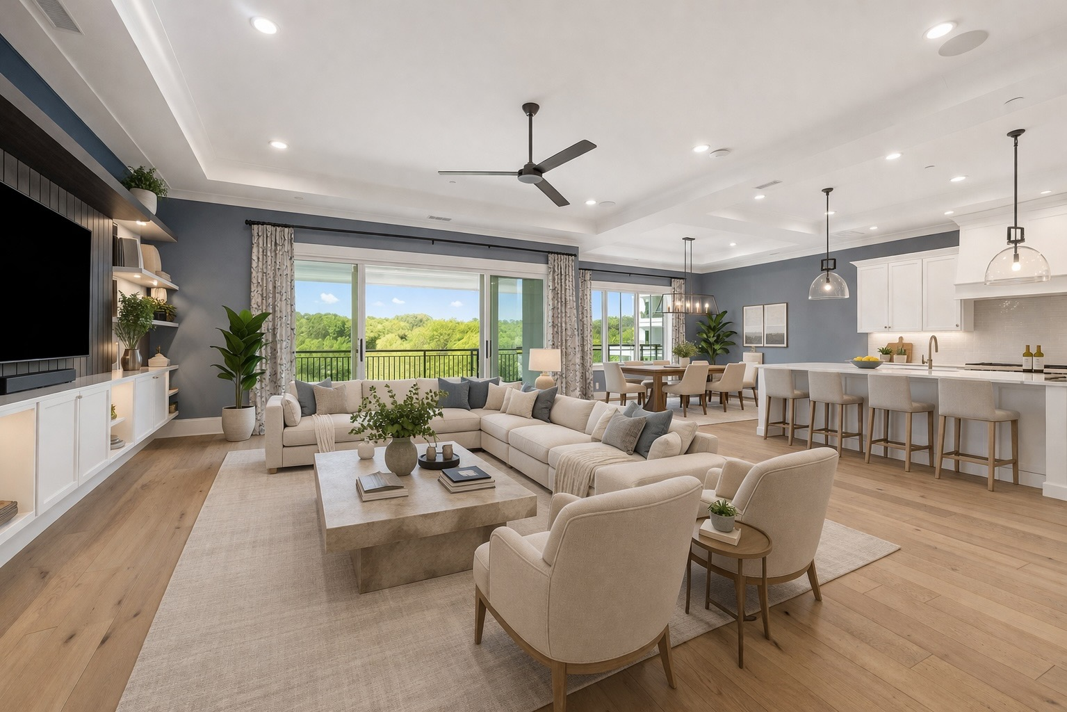 Open-concept living room, kitchen, and dining area with blue-grey accent walls and hardwood floors