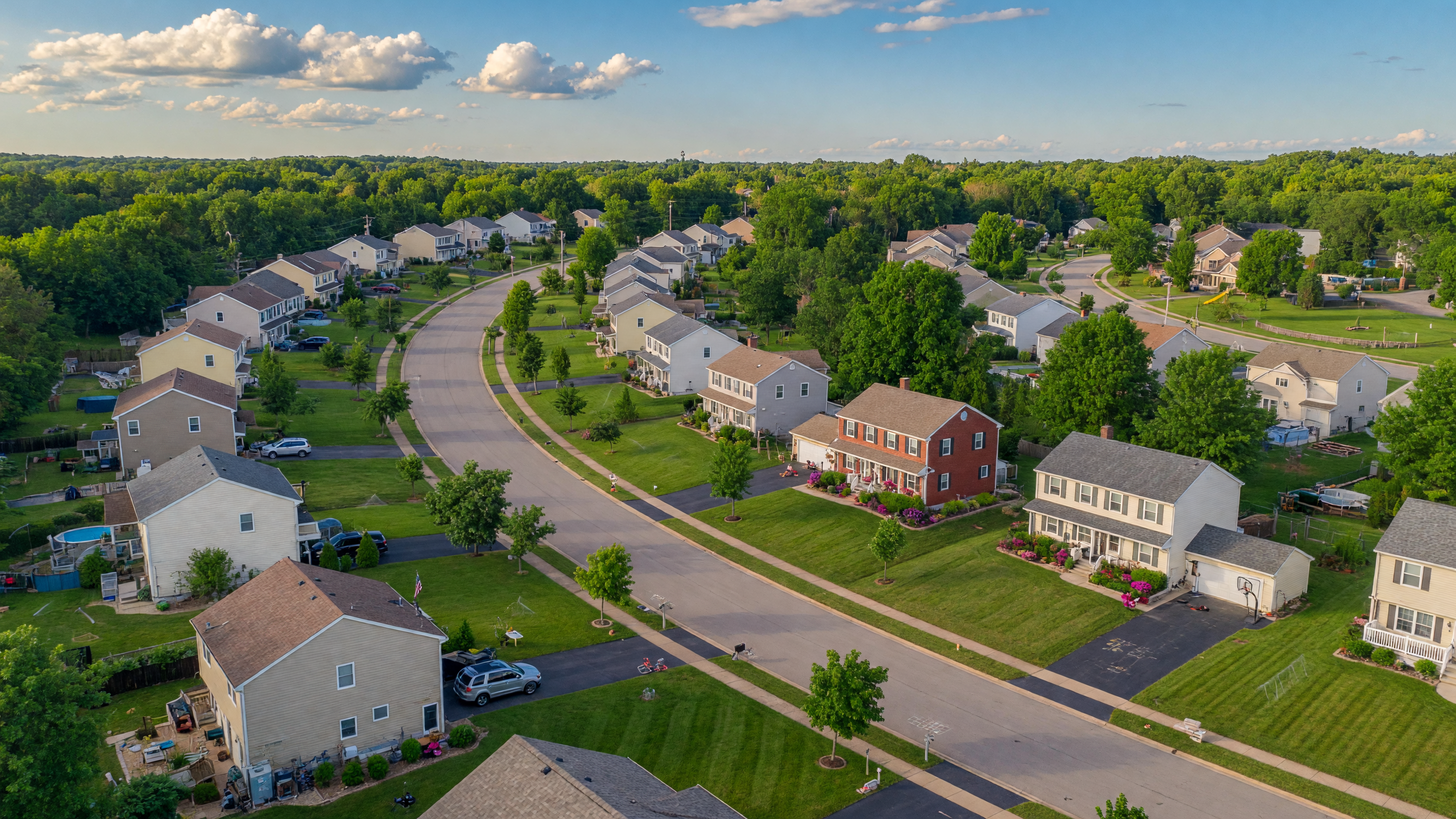 Aerial view of a tree-lined Mid-Michigan suburban neighborhood on a sunny summer day