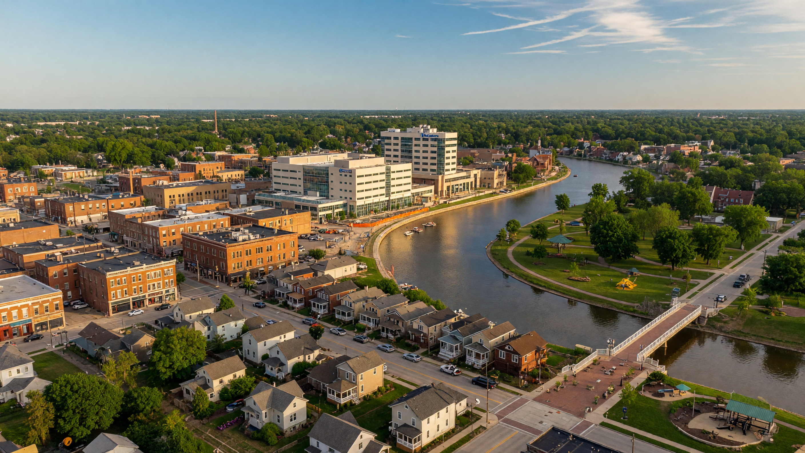 Aerial view of downtown Saginaw Michigan showing the Saginaw River, historic buildings, and surrounding tree-lined neighborhoods