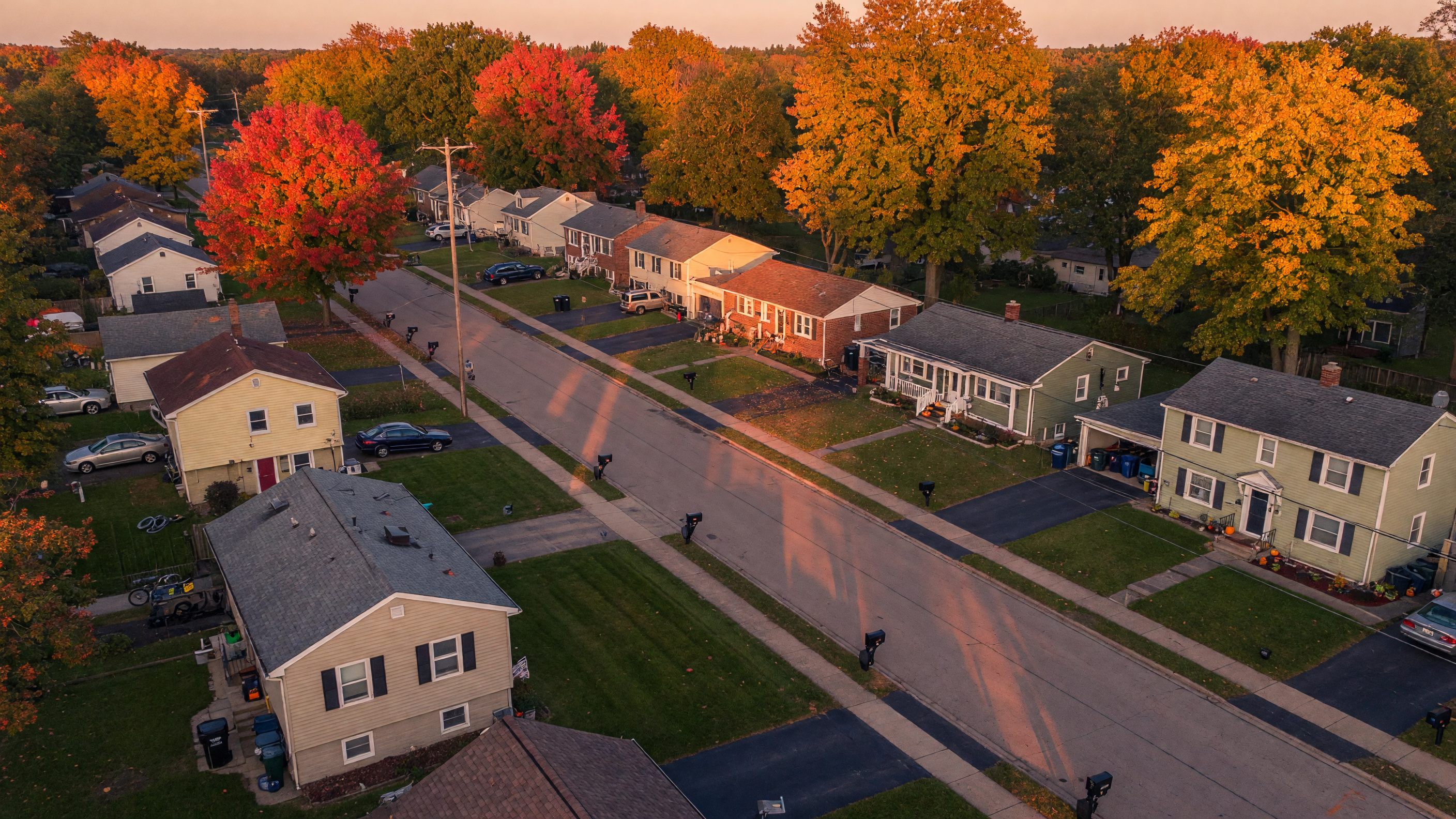 Aerial view of a Mid-Michigan residential neighborhood with well-maintained homes and mature trees at golden hour