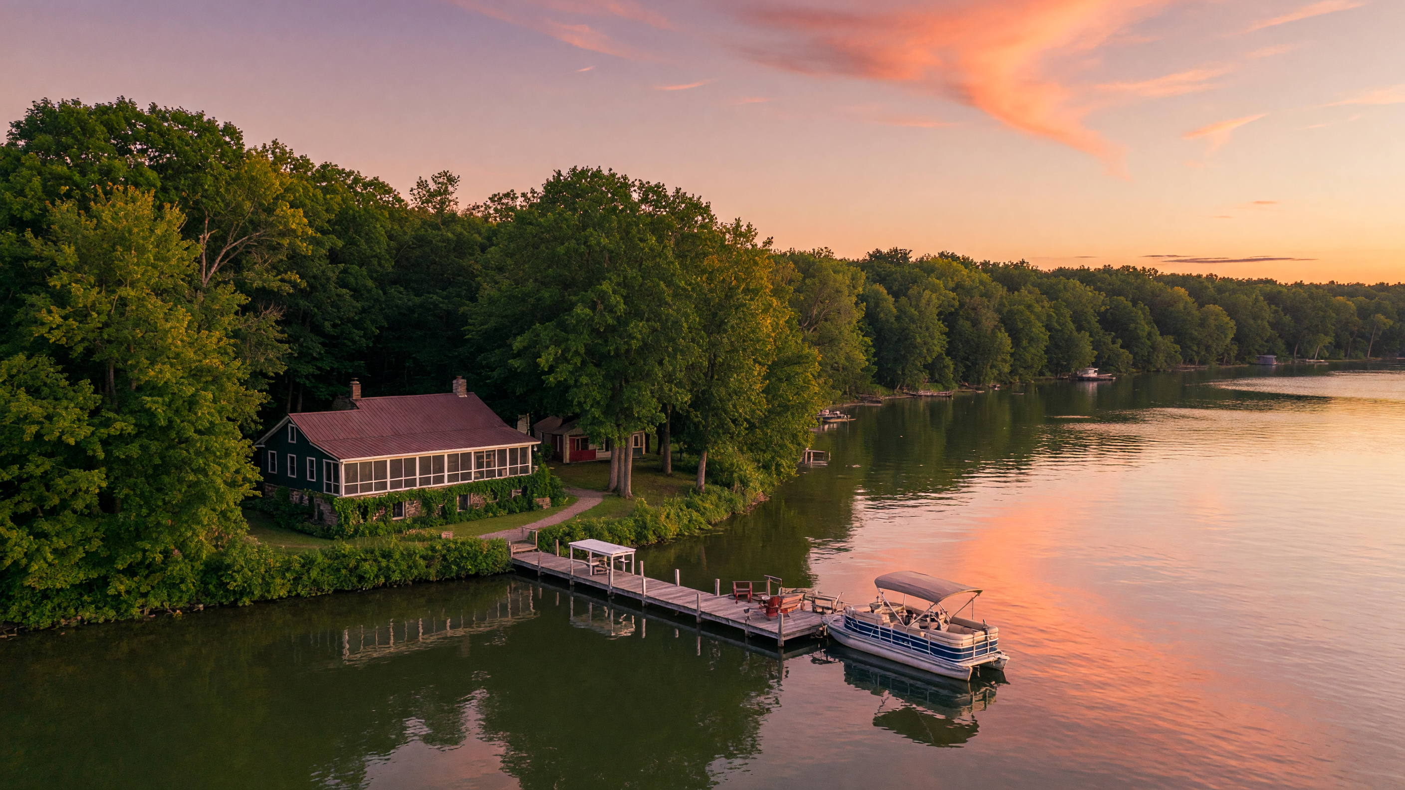 A beautiful lakefront home on a calm Michigan lake at golden hour with a wooden dock and mature trees