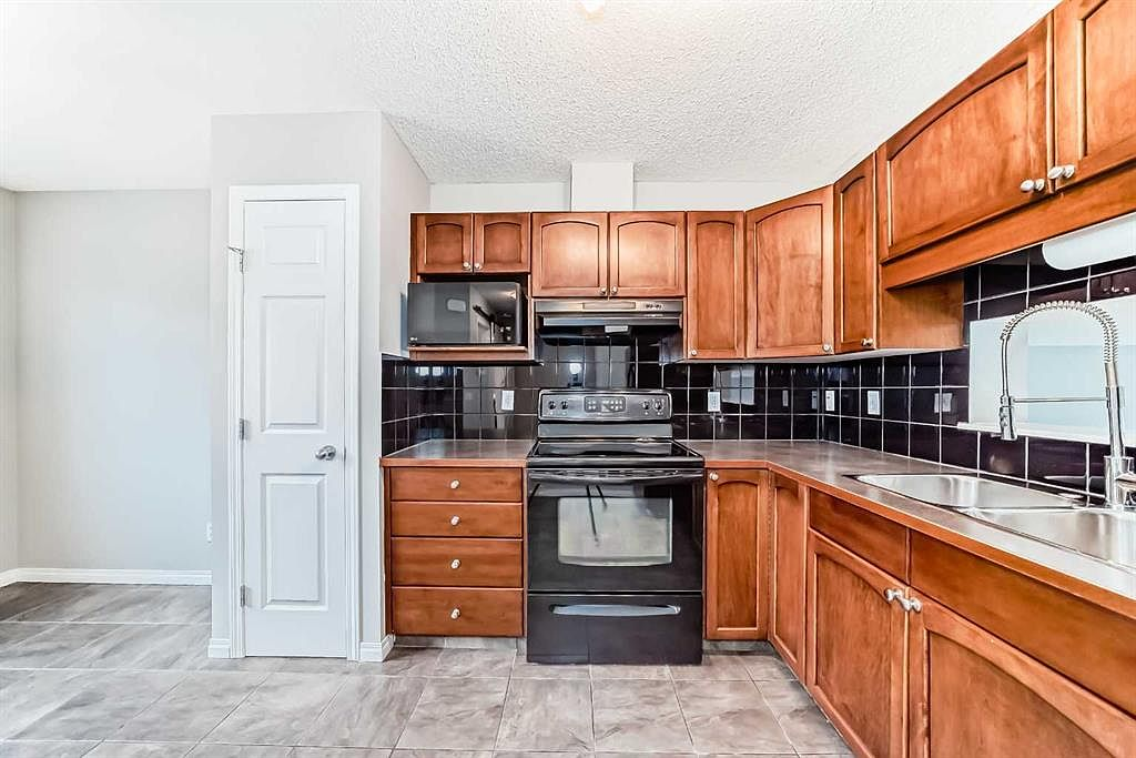 Kitchen with wood cabinetry and black tile backsplash