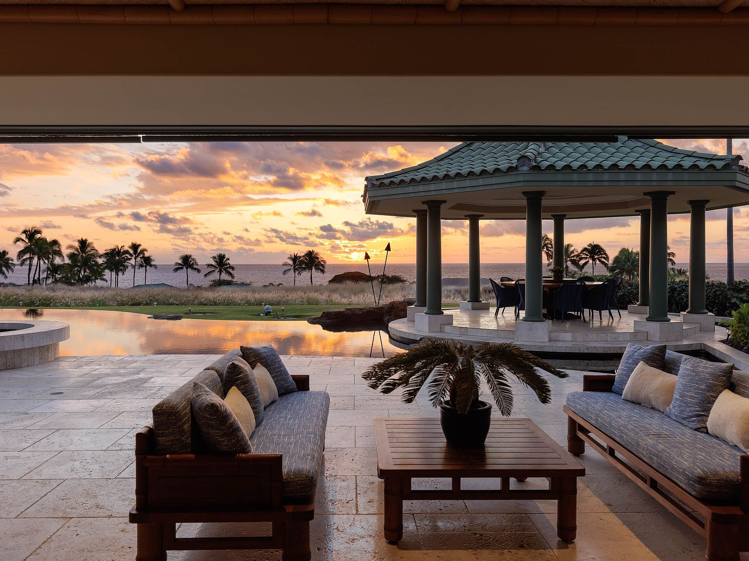 Covered lanai at sunset overlooking infinity pool and ocean