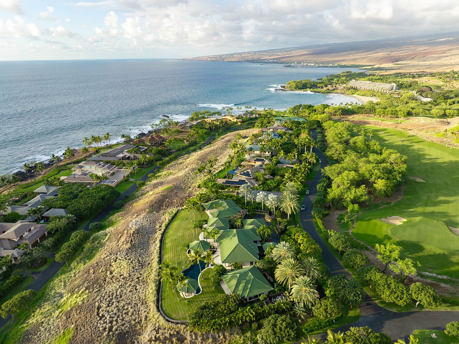 Aerial overlooking luxury coastal estate with golf course frontage and ocean view