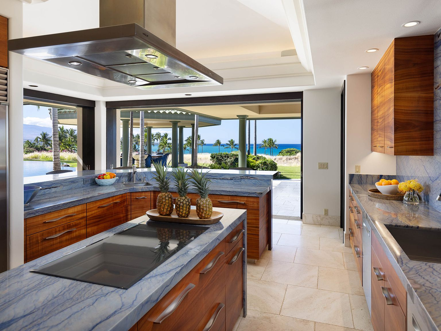 Kitchen with blue-veined marble countertops, warm wood cabinetry, and open ocean view