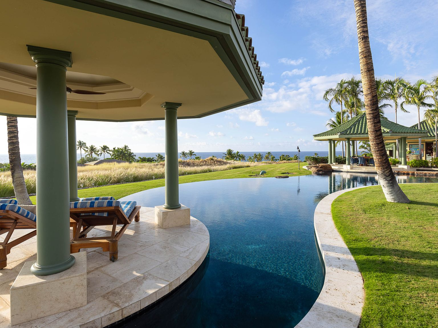 Infinity-edge pool with ocean view, tropical pavilion, palm trees
