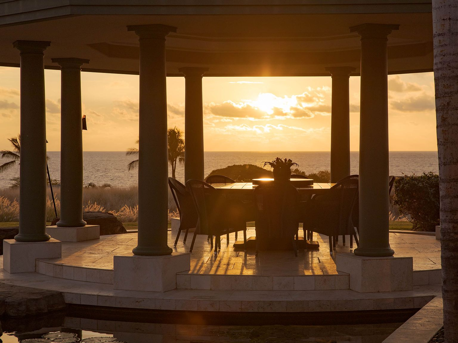 Circular outdoor dining pavilion at golden hour with ocean view