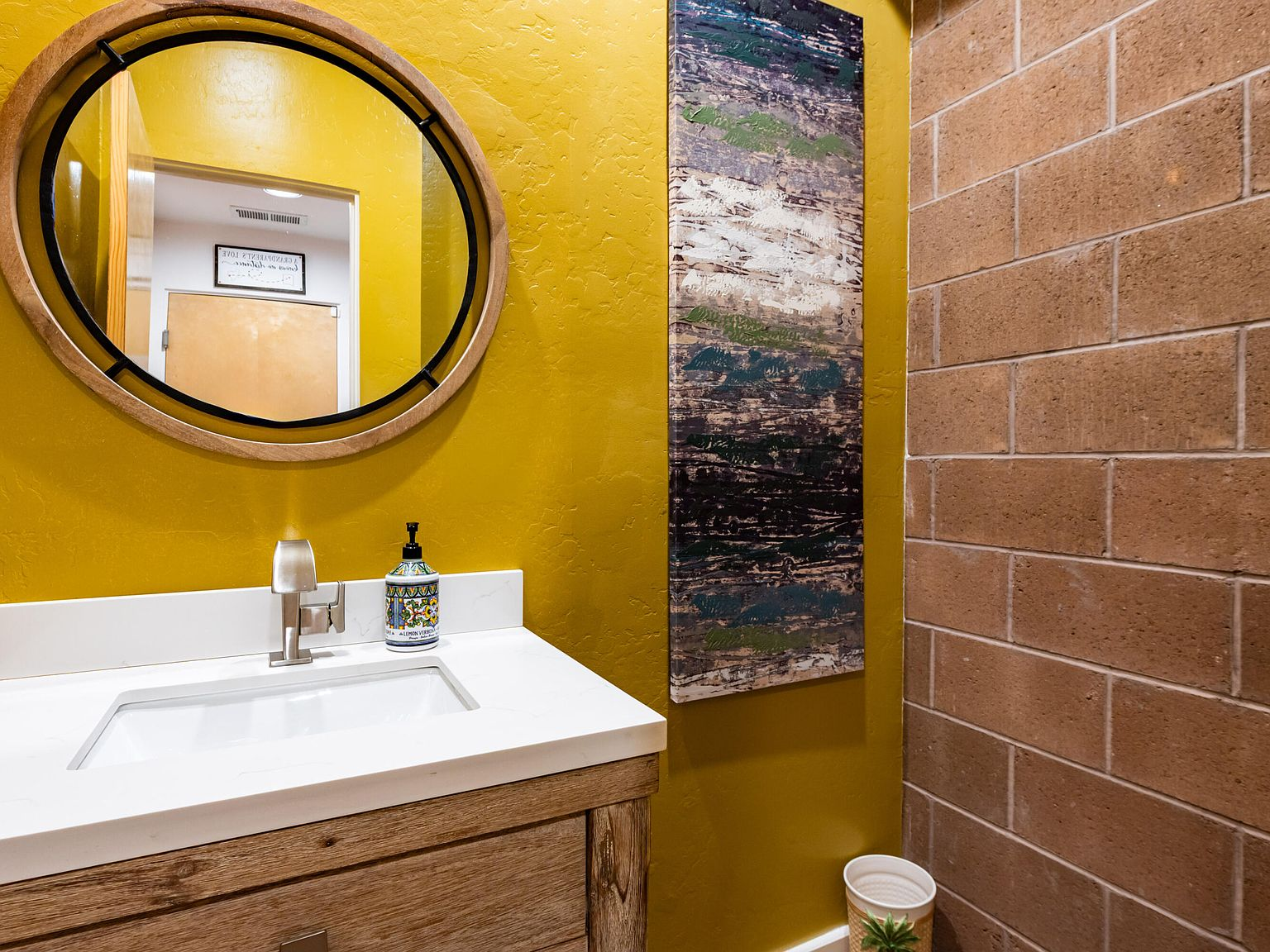 Bathroom vanity with textured yellow plaster wall and exposed block