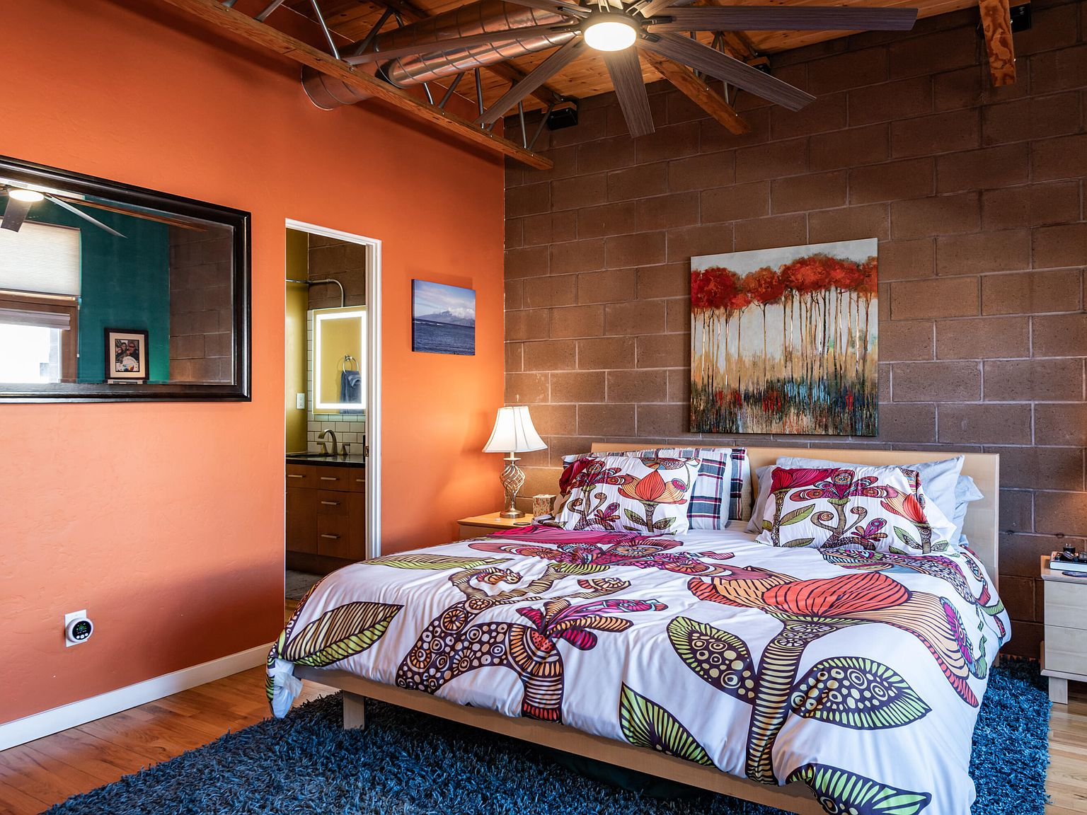 Primary bedroom with cinder block accent wall and wood flooring