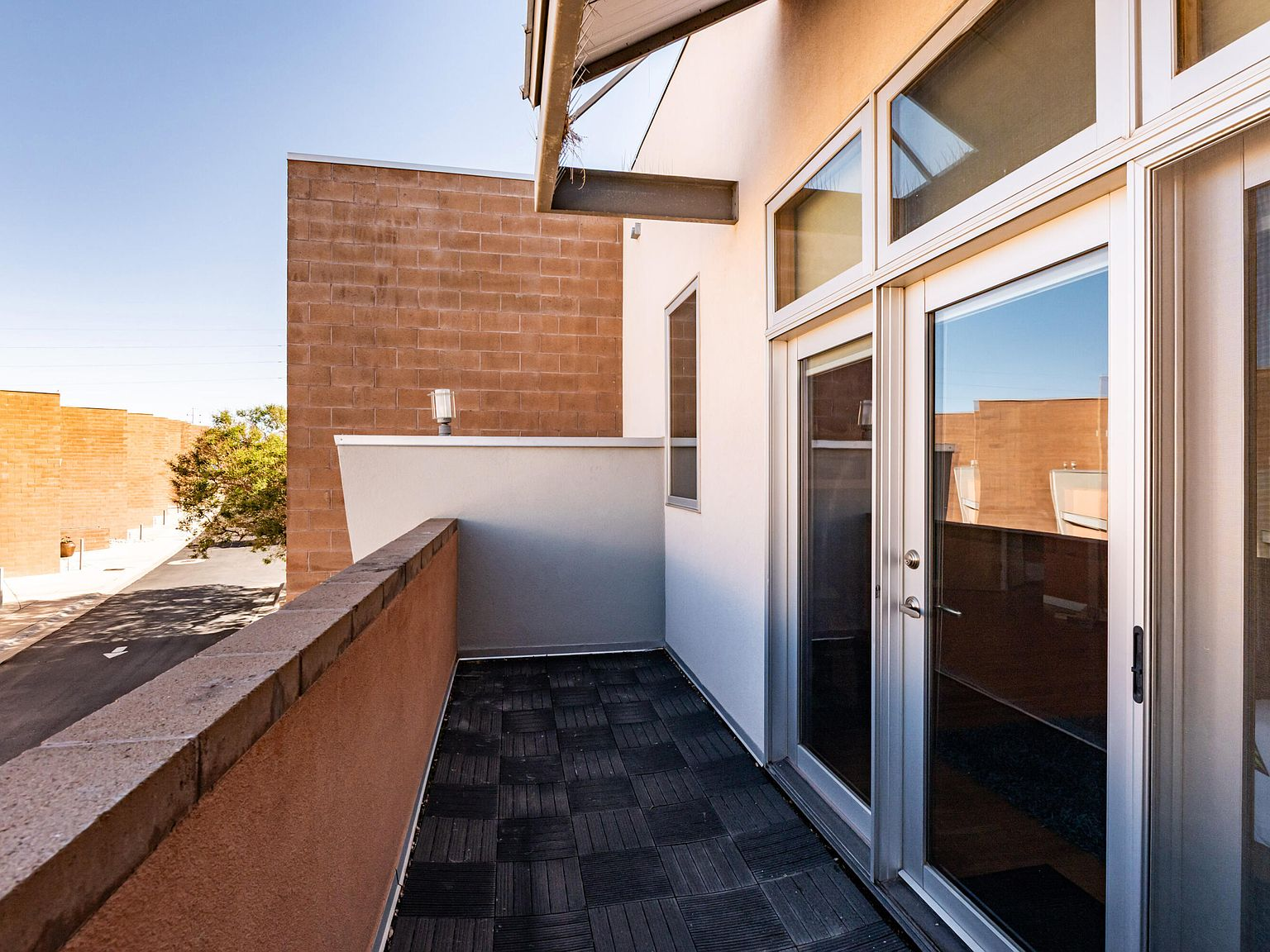 Private second-floor balcony with stucco walls and blue sky