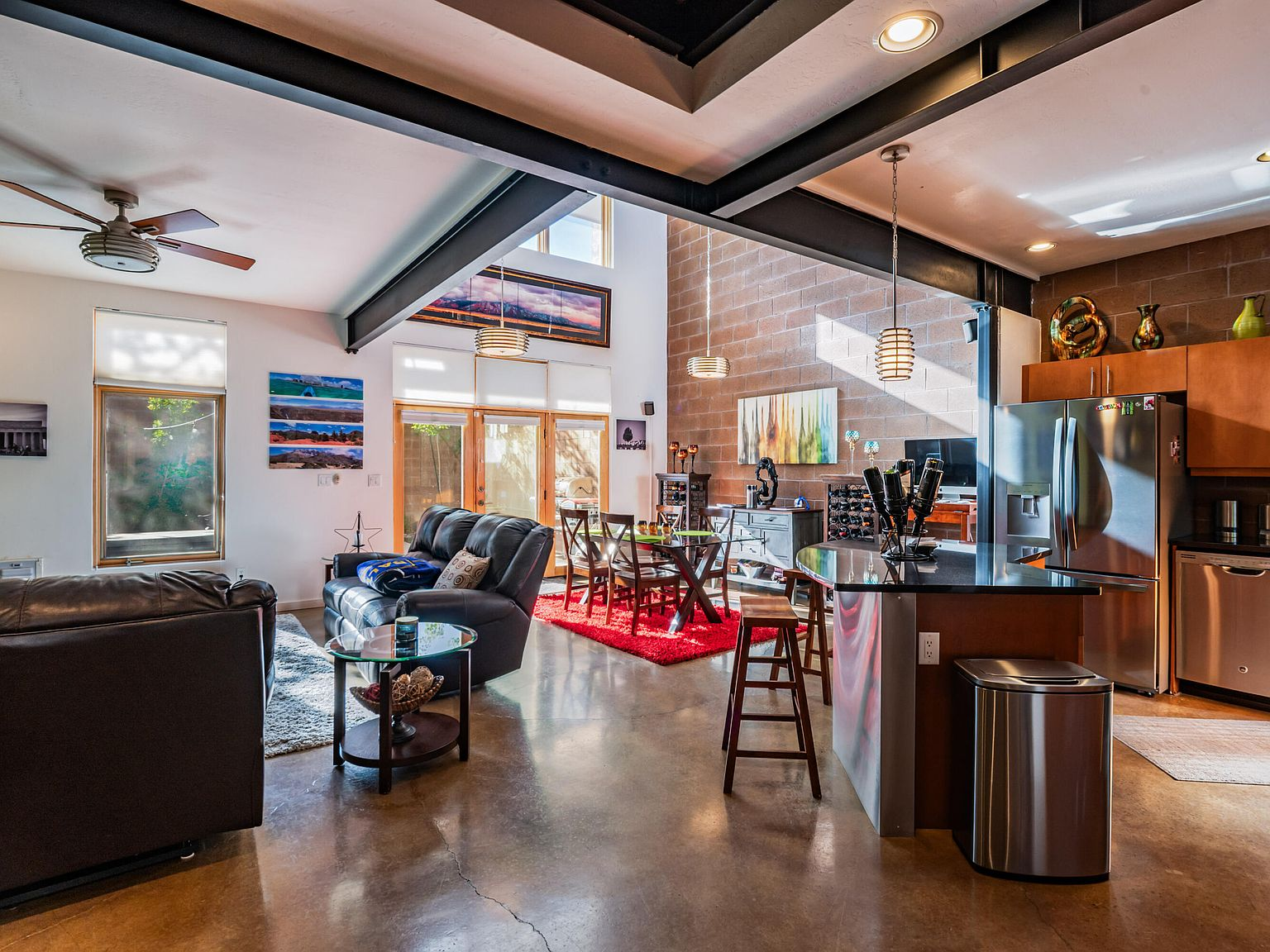 Open-concept great room with concrete floors, exposed steel I-beams, and kitchen