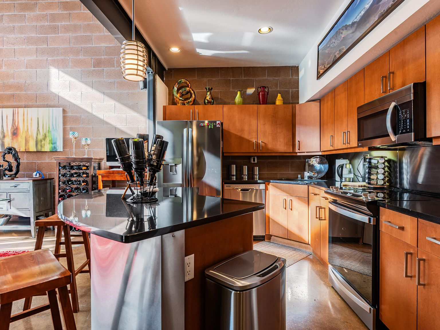 Contemporary kitchen with wood cabinets, black countertops, and breakfast bar island