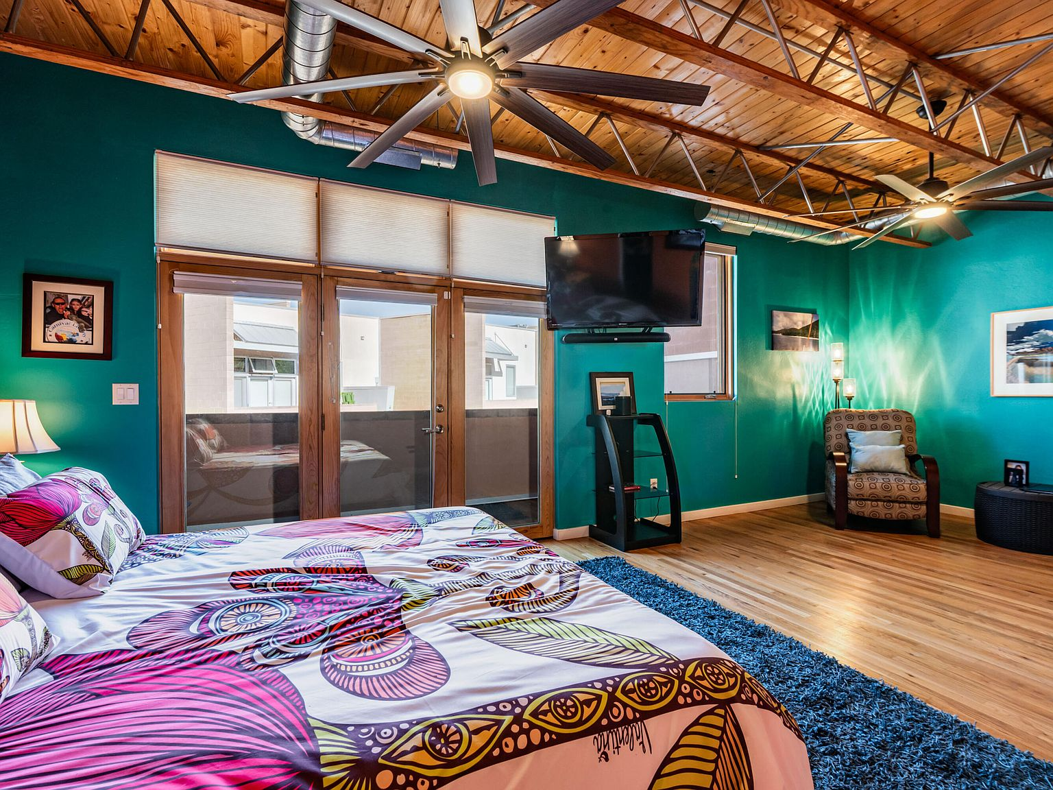 Primary bedroom with wood ceiling, trusses, and teal accent walls