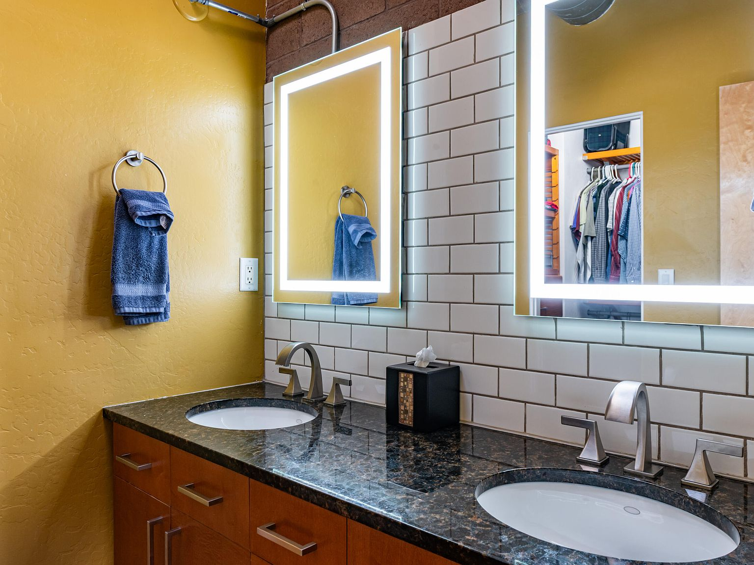 Bathroom with double vanity, subway tile, and brick accent wall