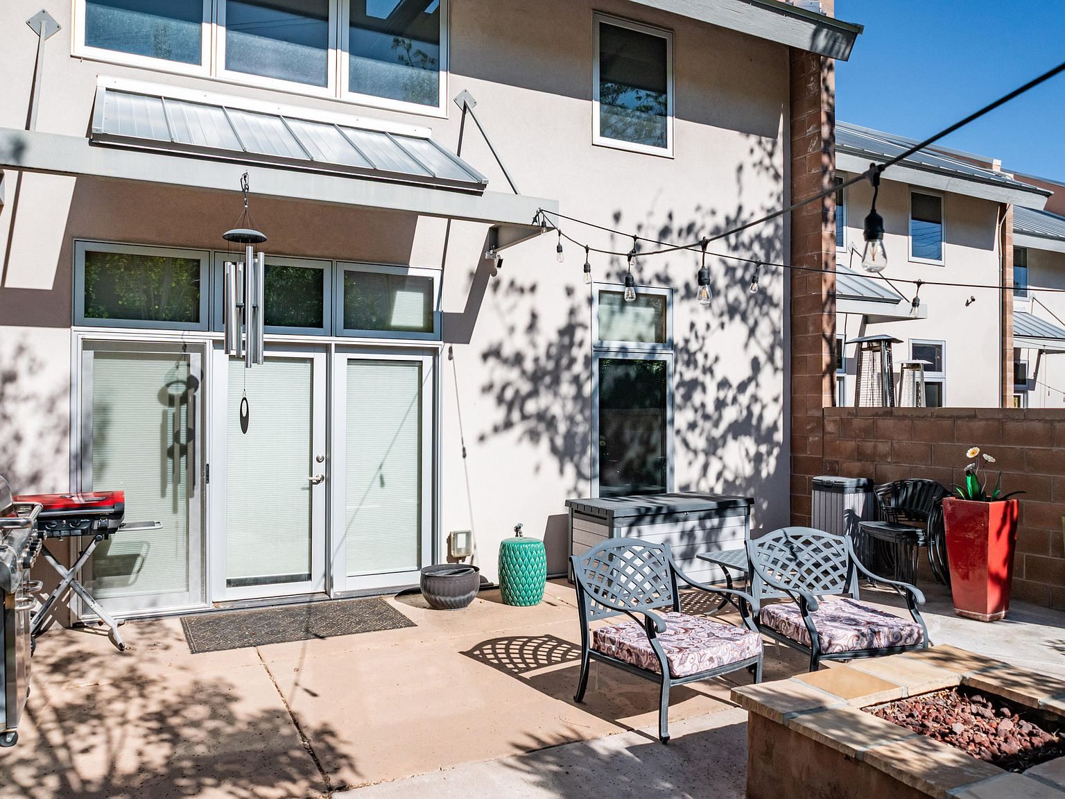 Walled backyard patio with concrete paving and awning