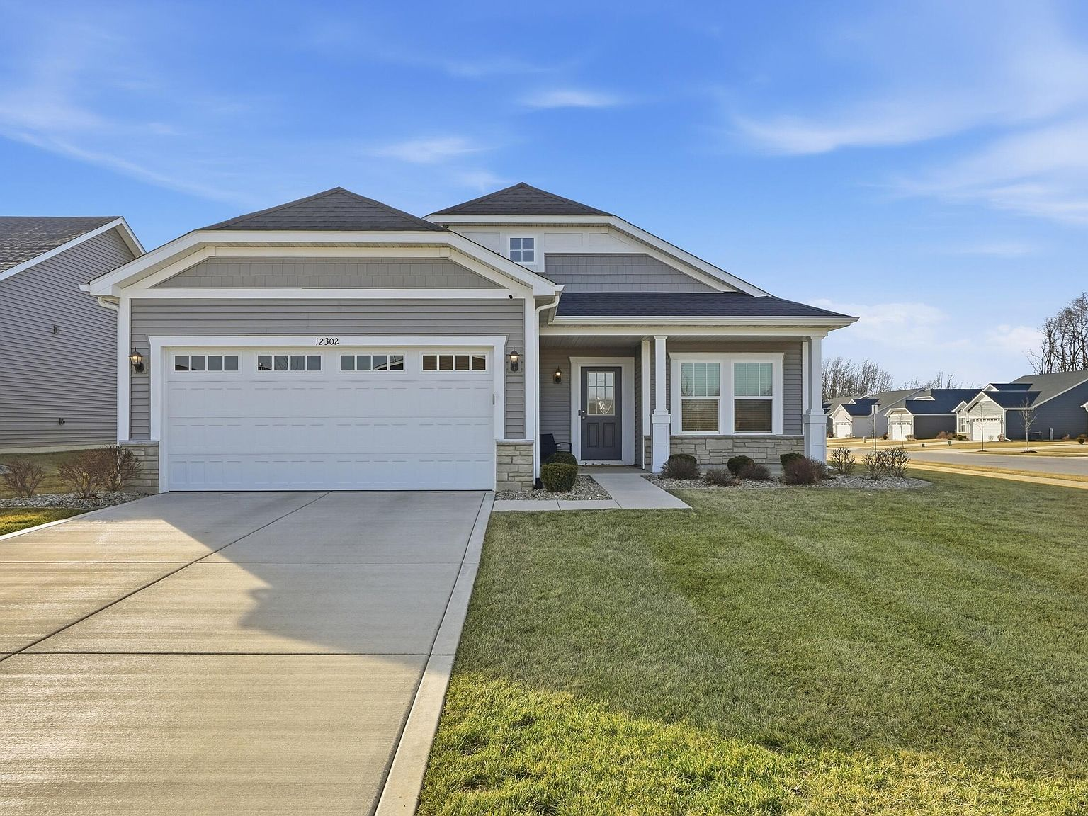 Front exterior of 12302 Ontario Pl, a modern ranch-style home with gray siding, stone veneer accents, and concrete driveway