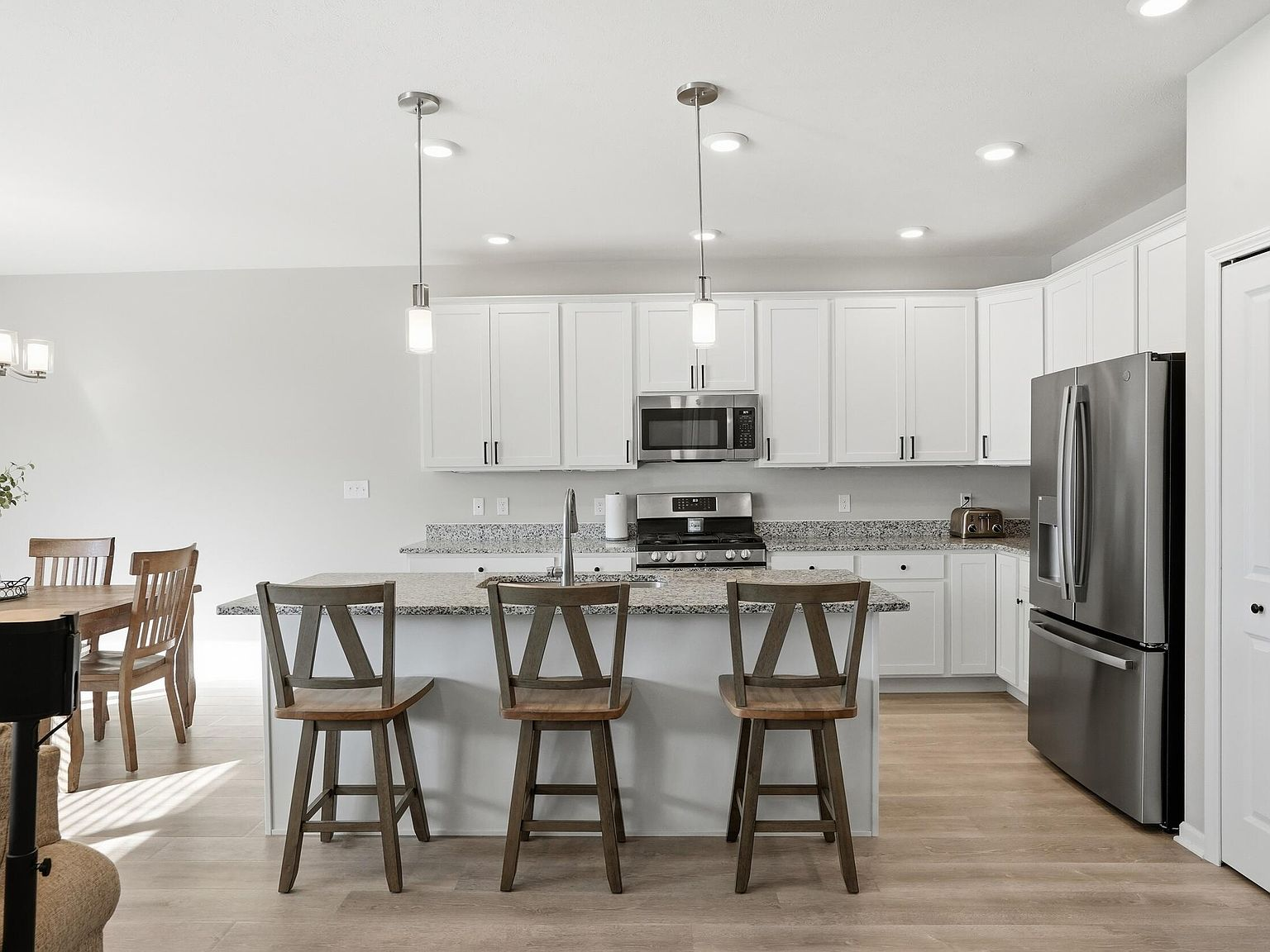 Kitchen with white shaker cabinets, granite countertops, and stainless steel appliances