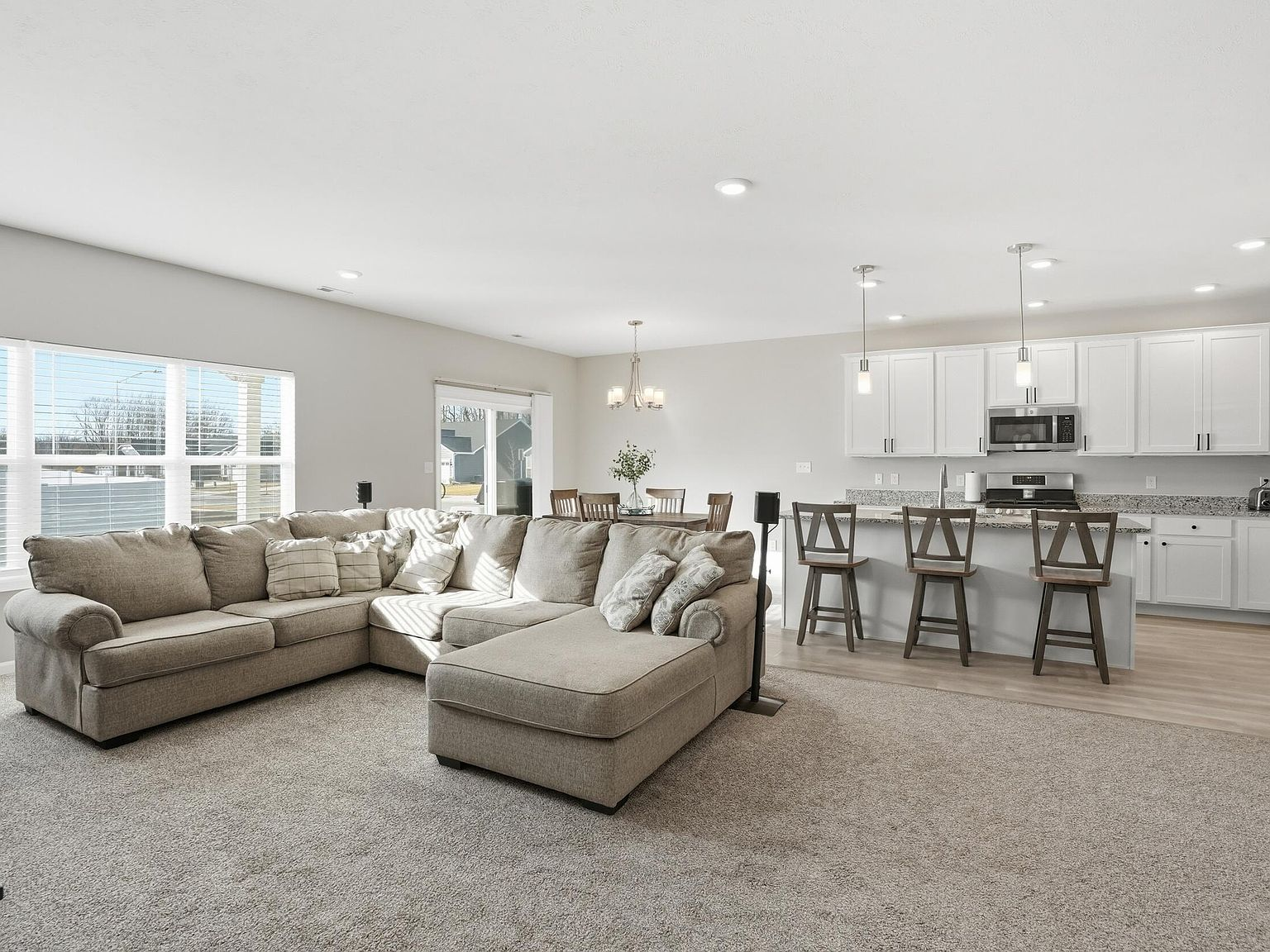 Spacious open-concept living room with carpet and wood laminate flooring