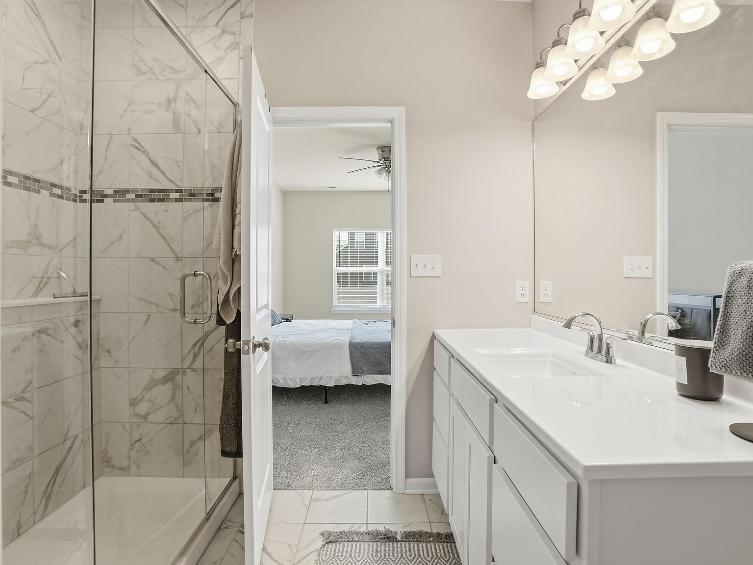 Primary bathroom with double vanity, white cabinetry, and large mirror
