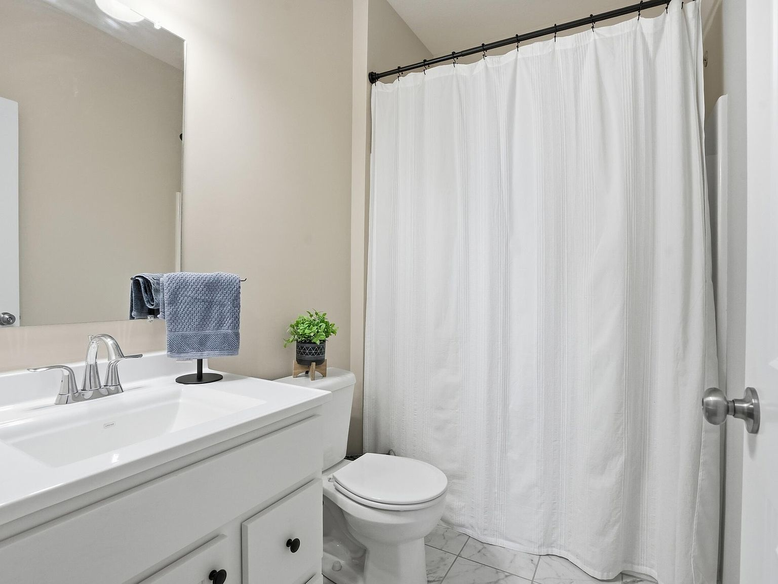 Second bathroom with white single-sink vanity and enclosed shower area