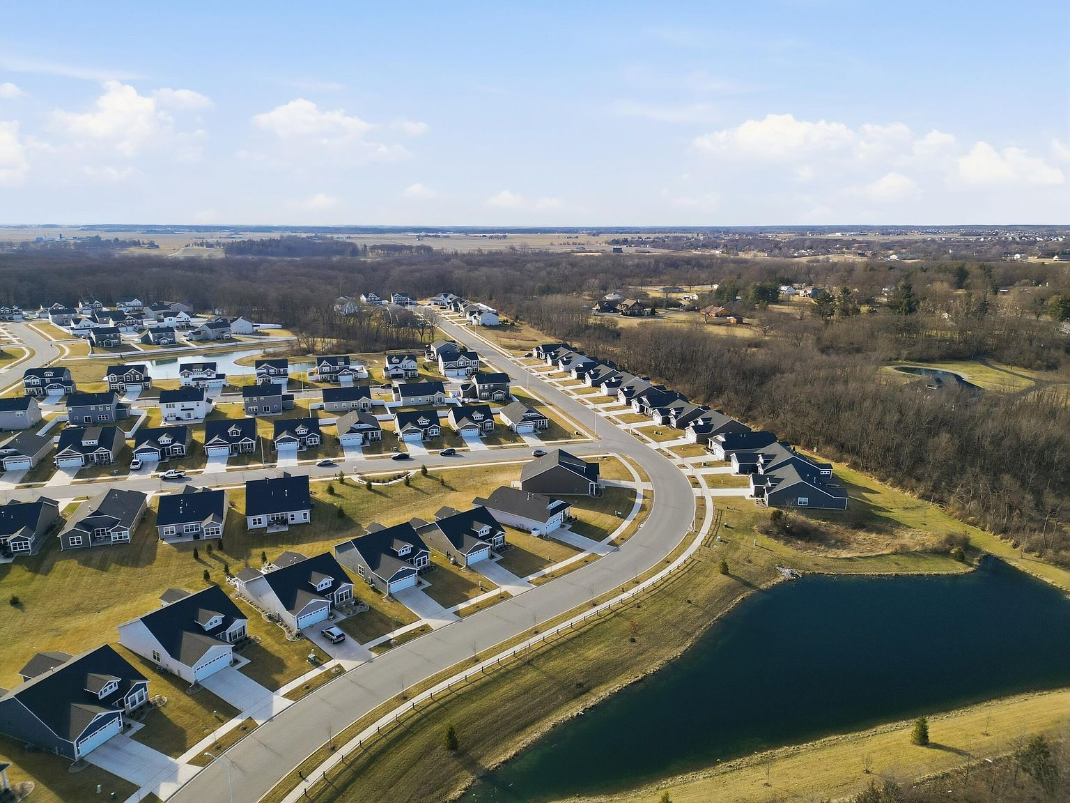 High-angle drone aerial of Cedar Lake suburban subdivision with curved roads and retention pond