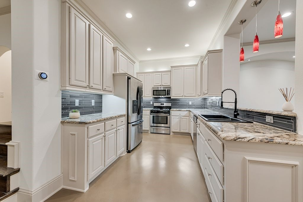 Modern kitchen with granite countertops, white cabinetry, and under-cabinet lighting