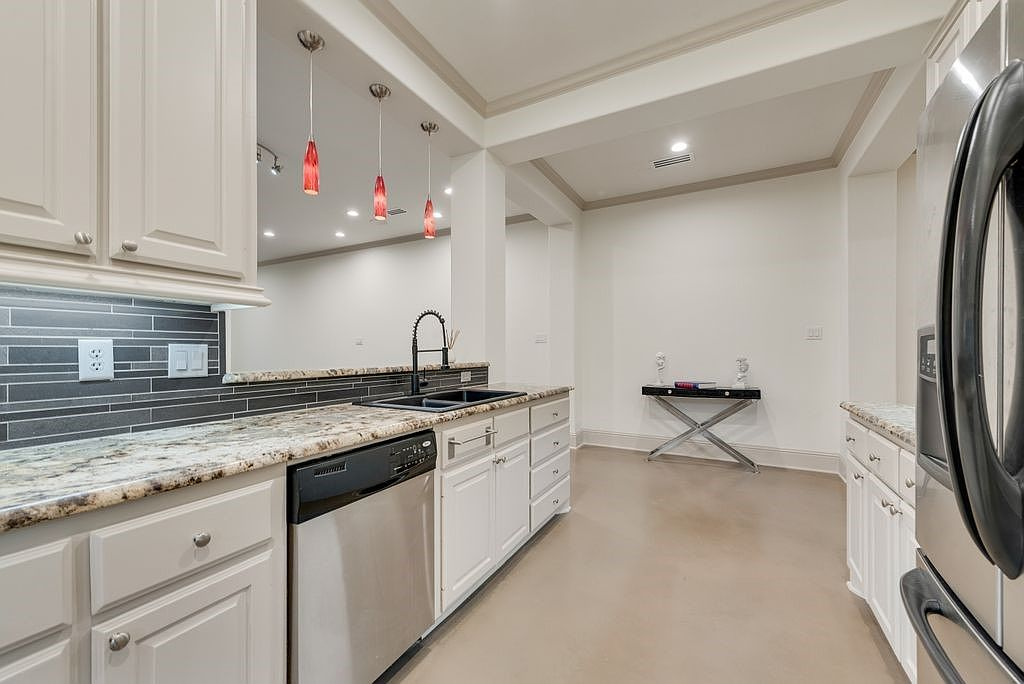Kitchen showing granite countertops, white cabinetry, and stainless steel dishwasher