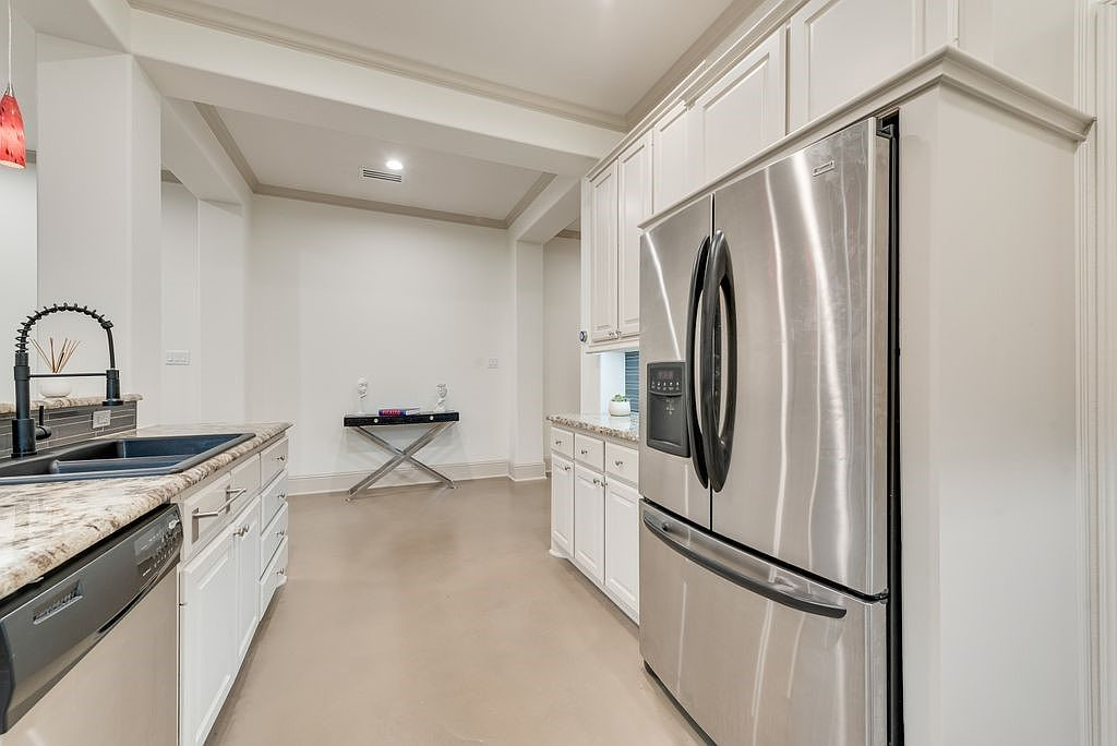 Kitchen with stainless steel refrigerator, granite countertops, and white painted cabinets