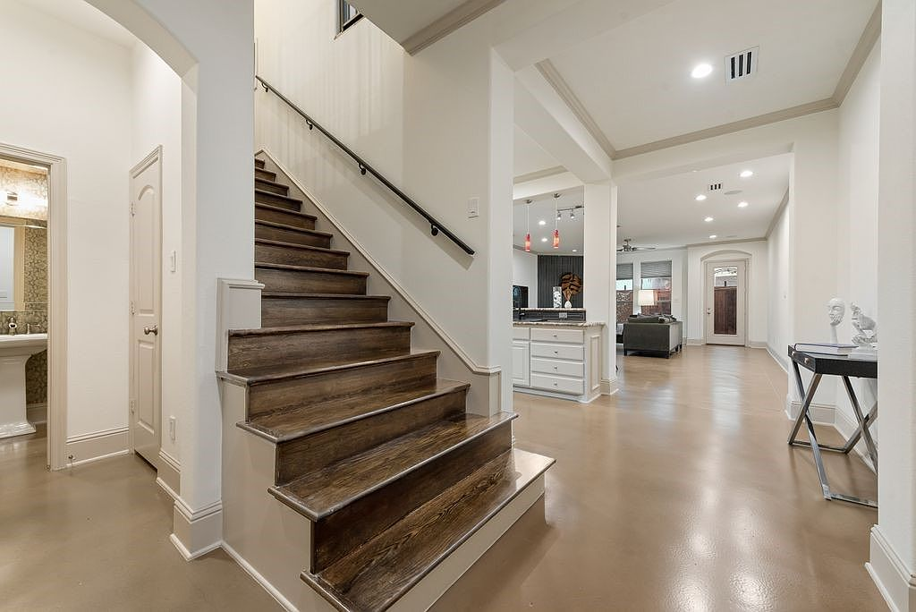 Entryway showing the staircase and open-concept main floor with stained concrete