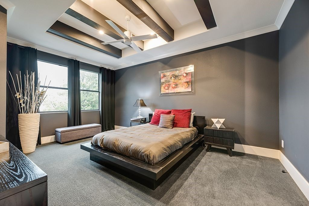 Primary bedroom with dark wood accent beams and charcoal walls