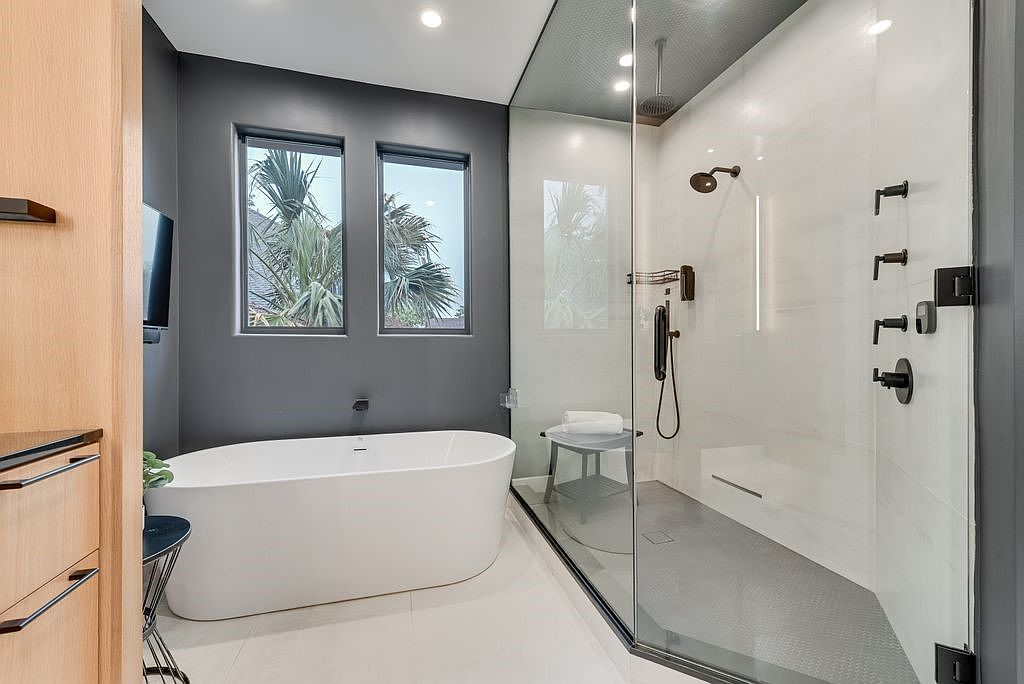 Bathroom with freestanding tub and large glass-enclosed steam shower with dark gray accent walls