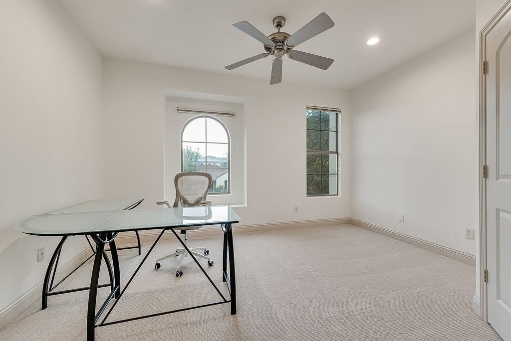 Guest bedroom with arched window, neutral white walls, and beige carpet