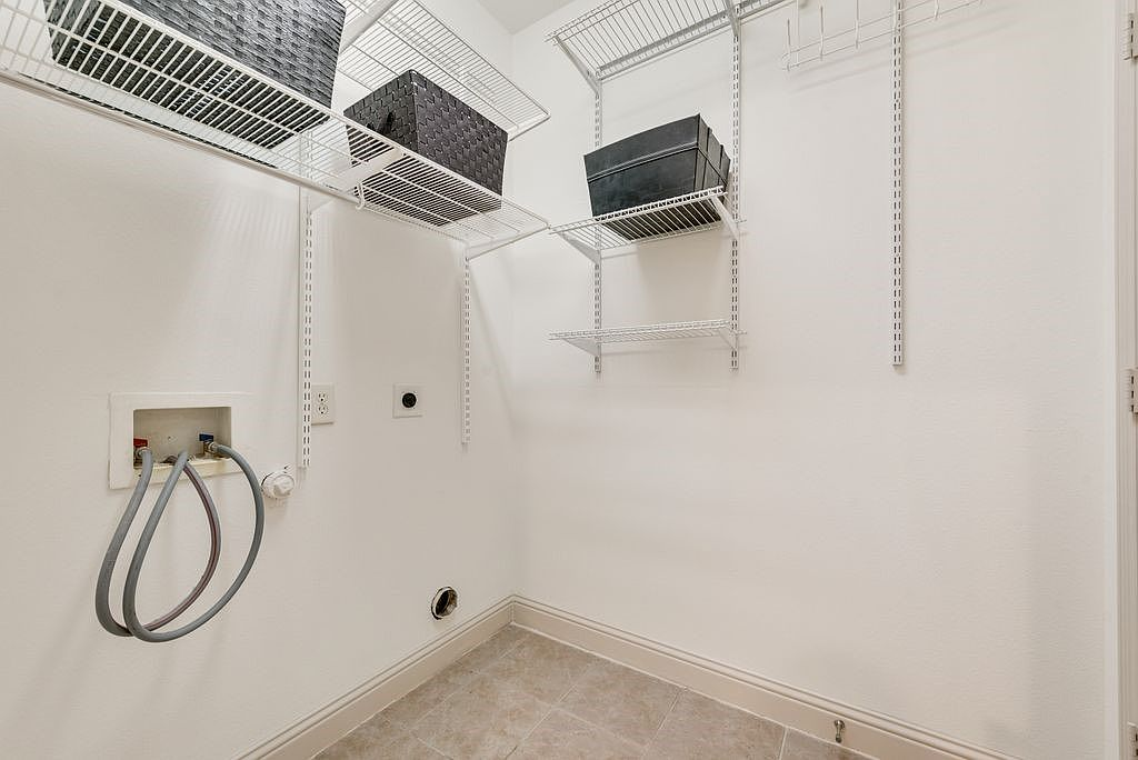 Laundry and utility room with wire shelving and beige tile floor