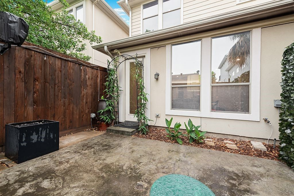 Back patio courtyard with stucco exterior, concrete floor, and wood fence