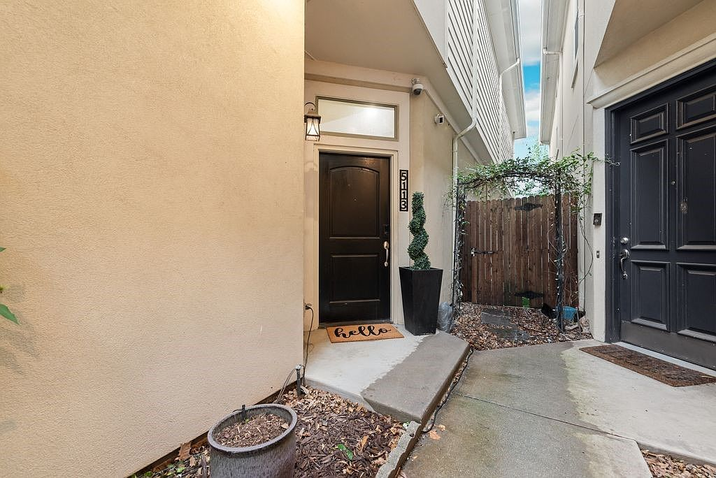 Front entrance of the townhome with black door and concrete pathway