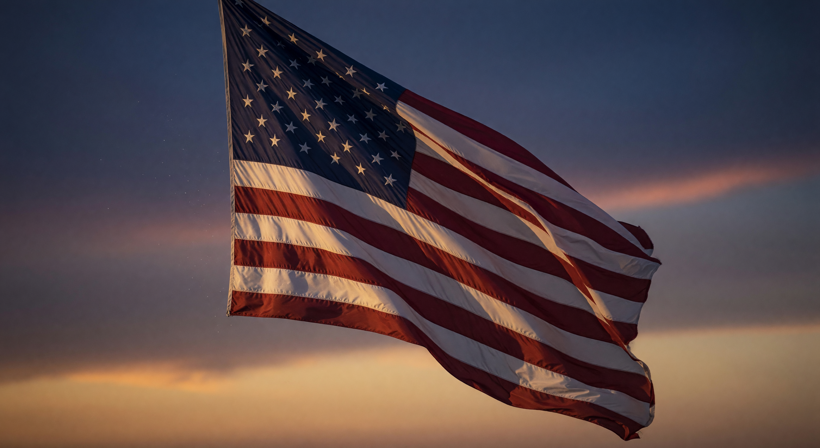 American flag waving against a twilight sky