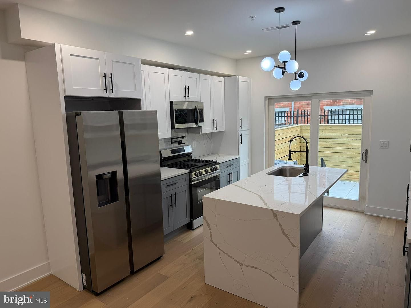Kitchen featuring white quartz waterfall island and premium stainless steel appliances