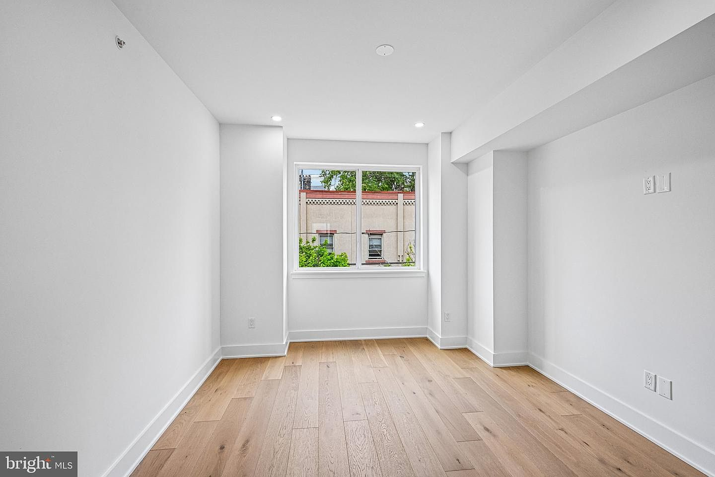 Empty bedroom with recessed lighting and warm afternoon light coming through a window