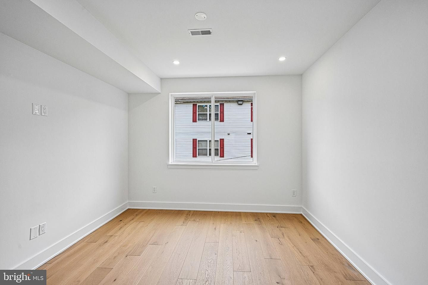 Sleek vacant bedroom facing window with crisp white walls and custom modern outlet frames