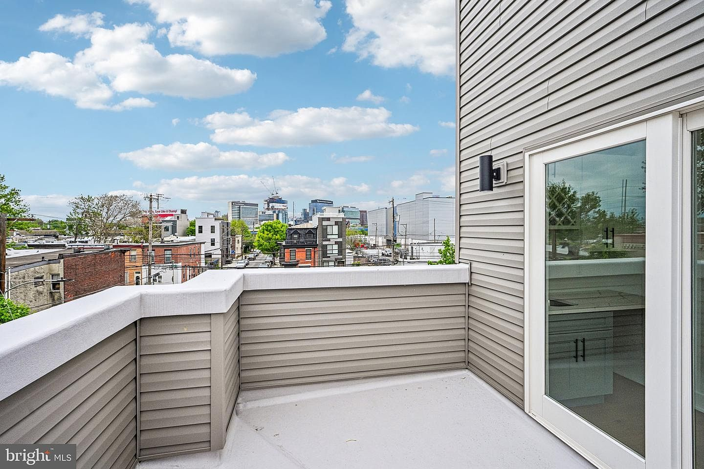 Wide perspective of modern rooftop deck with grey paneled railings overlooking adjacent buildings