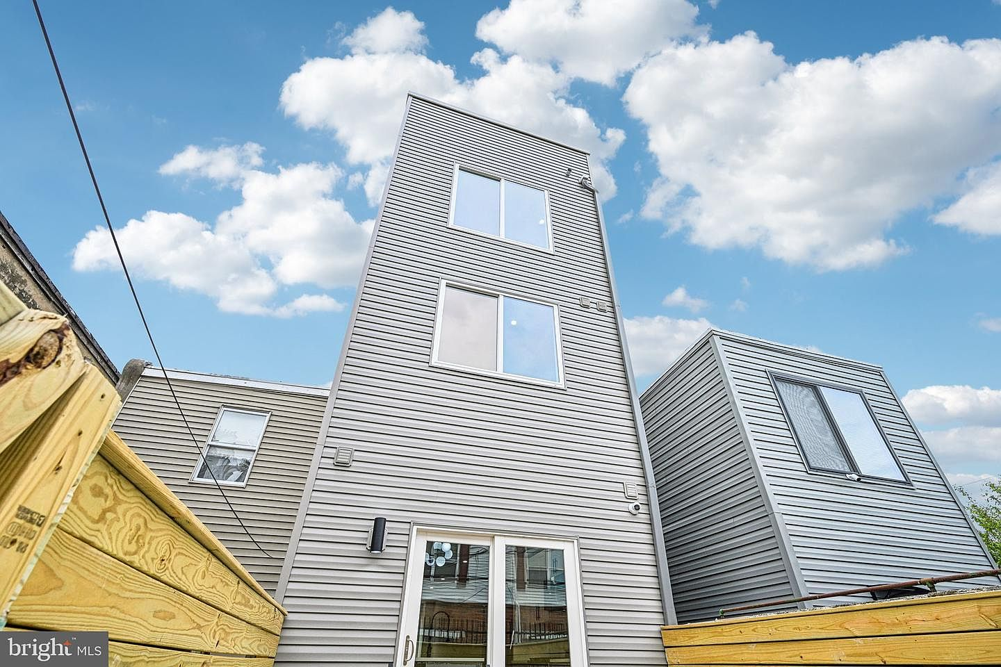 Rear exterior view looking up towards the three upper stories of the grey sided rowhouse