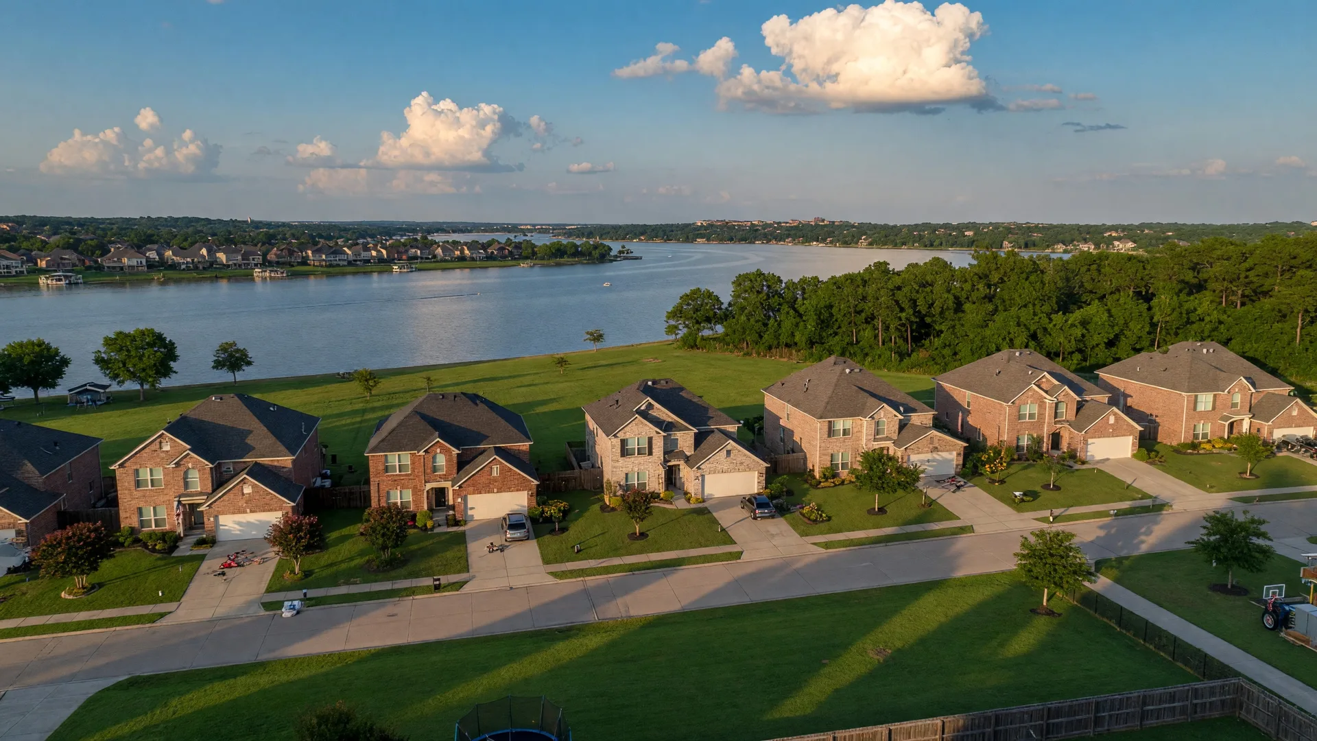 Aerial view of Sycamore Cove neighborhood near Lake Lewisville at golden hour with brick homes and tree-lined streets
