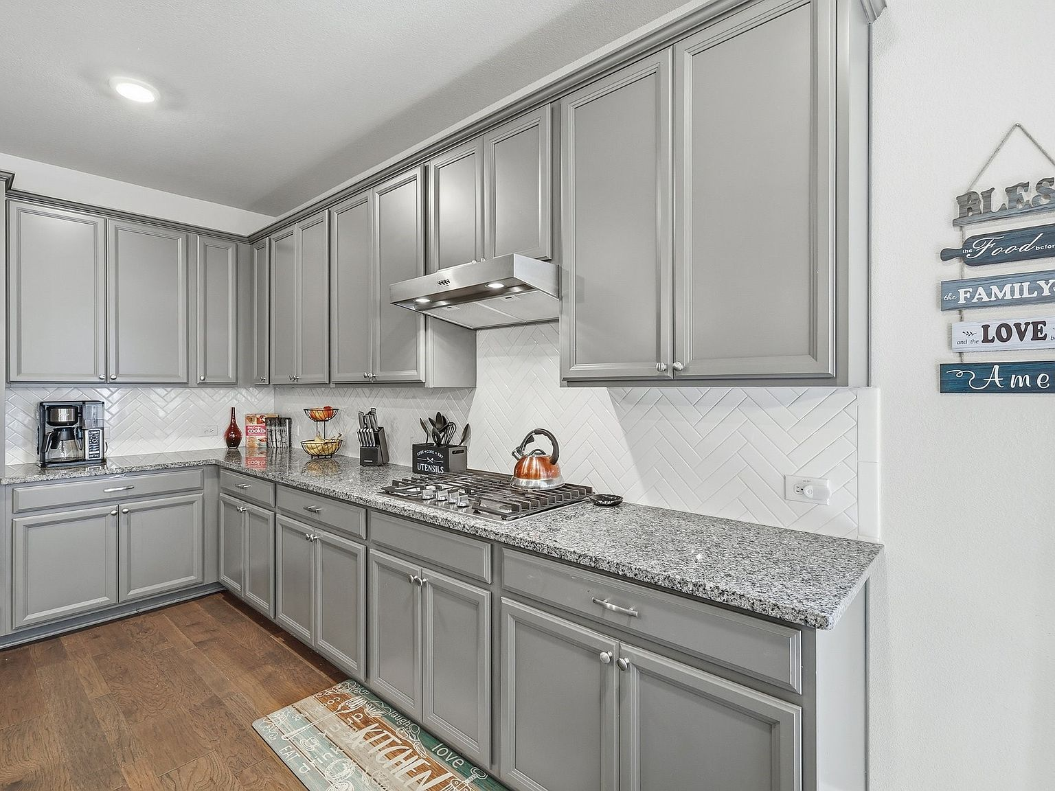 Kitchen detail showing grey shaker cabinets, granite countertops, and herringbone backsplash