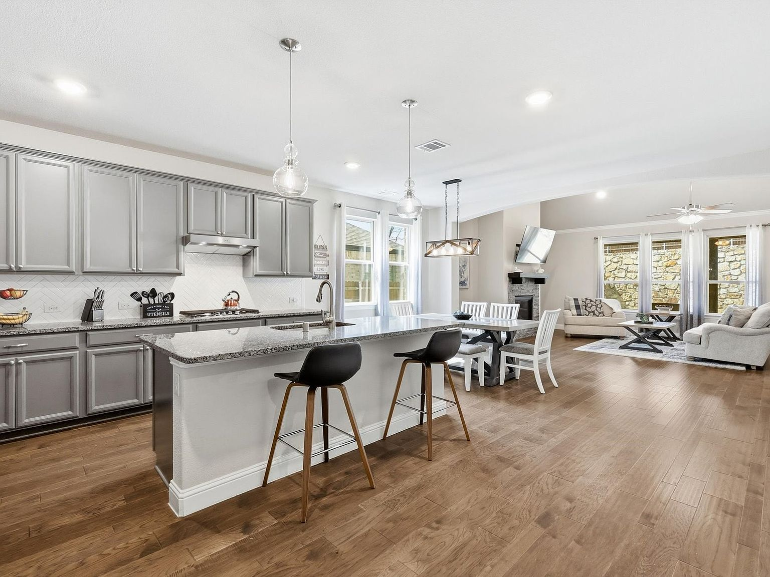 Open-concept kitchen with granite countertops, wood floors, and island seating
