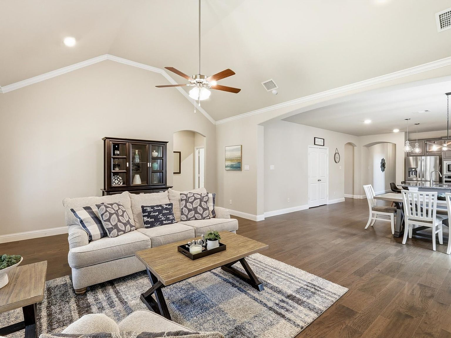 Wide-angle view of the open-concept living room flowing into dining and kitchen