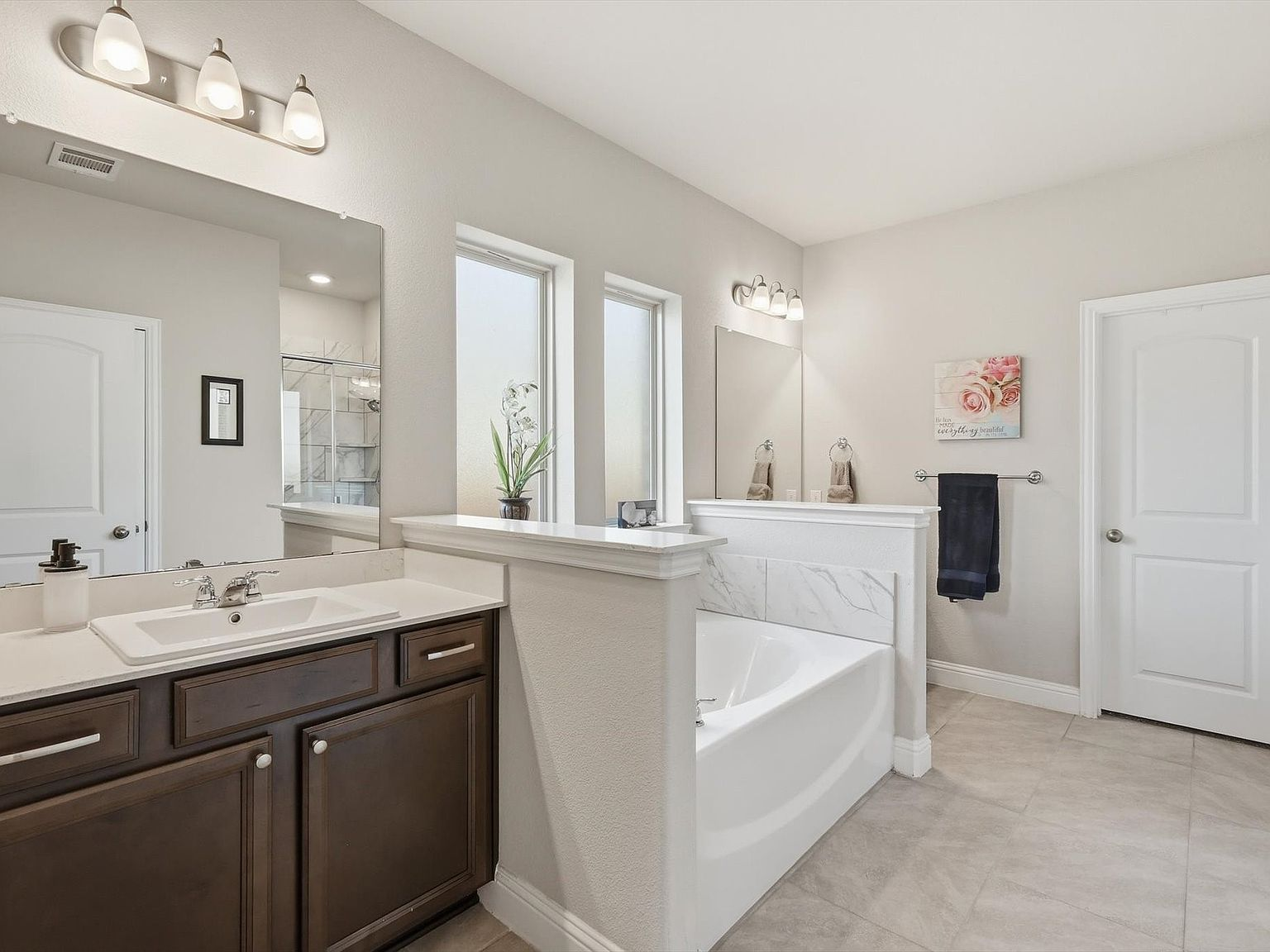Master bathroom with soaking tub, dark wood vanity, and tile flooring