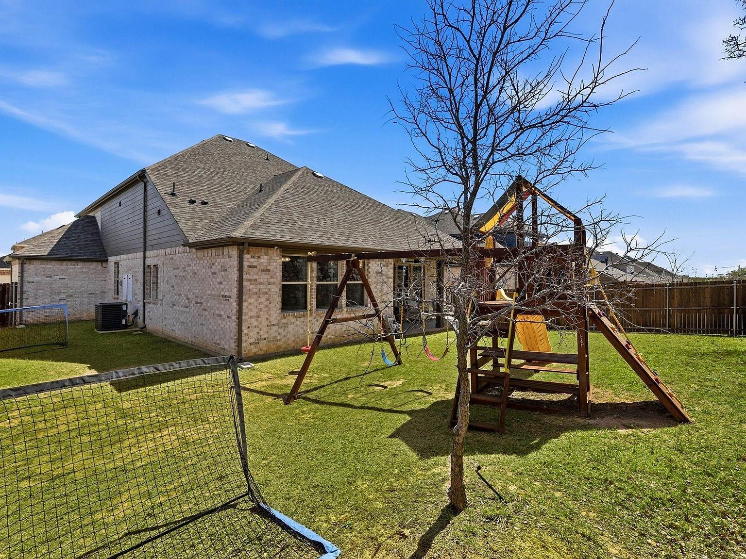 Backyard view toward the house with playset and lawn