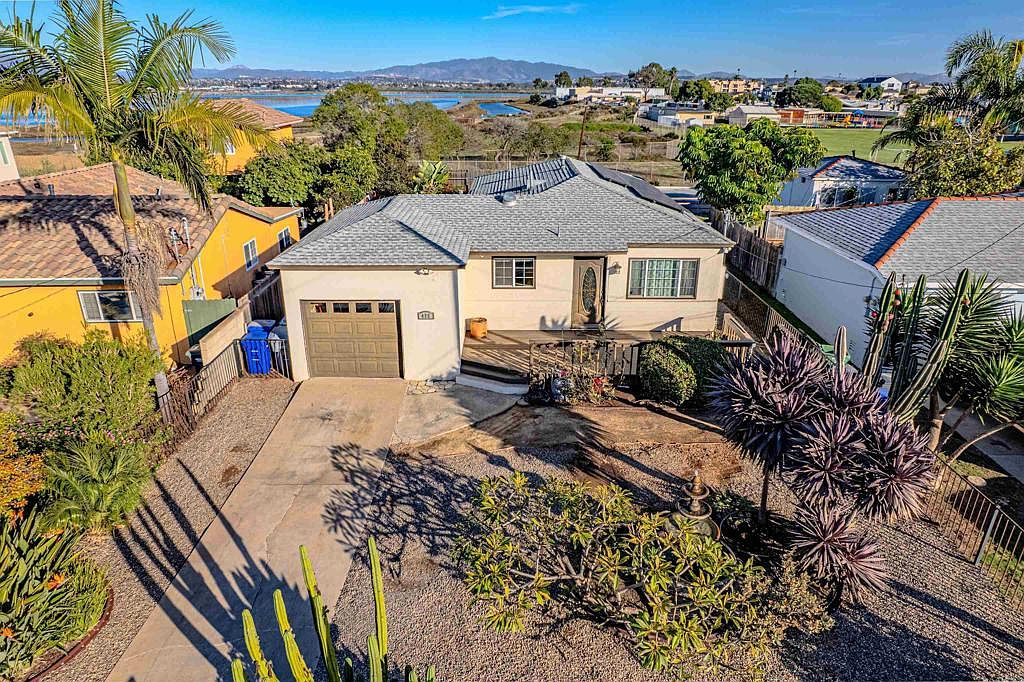 High-angle aerial of the front facade with xeriscaped yard and bay in the distance
