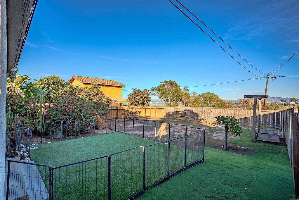 Backyard with artificial turf and bay views beyond the fence