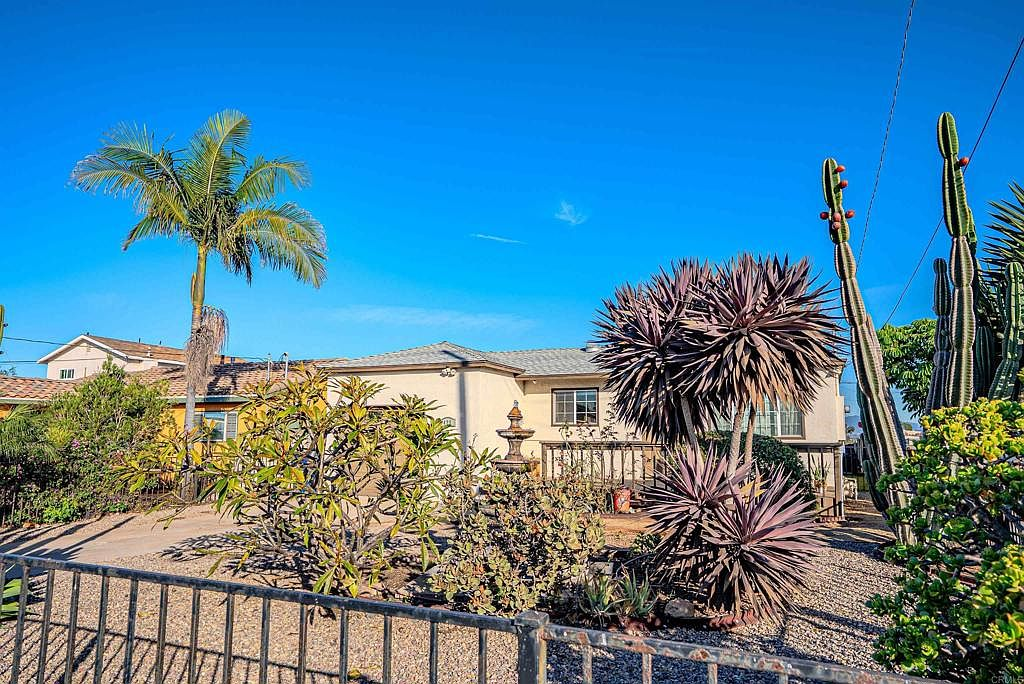 Front yard with desert landscaping, palm tree, and raised wooden deck